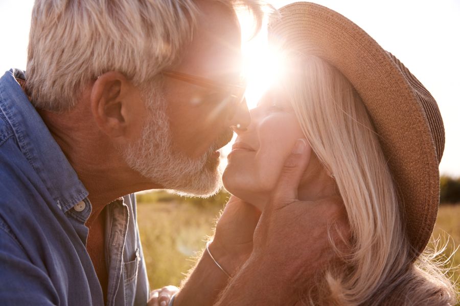 an older couple kiss in front of setting sun